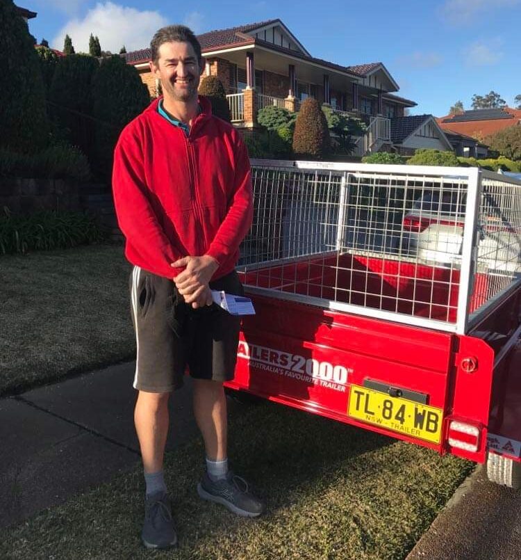 Adam McKenzie standing beside his Trailer2000 red box trailer - a first prize win from the Hunter Valley branch of the LANSW Father's Day raffle draw. 