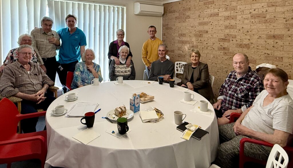 Group of laryngectomees and partners sitting round a circular table